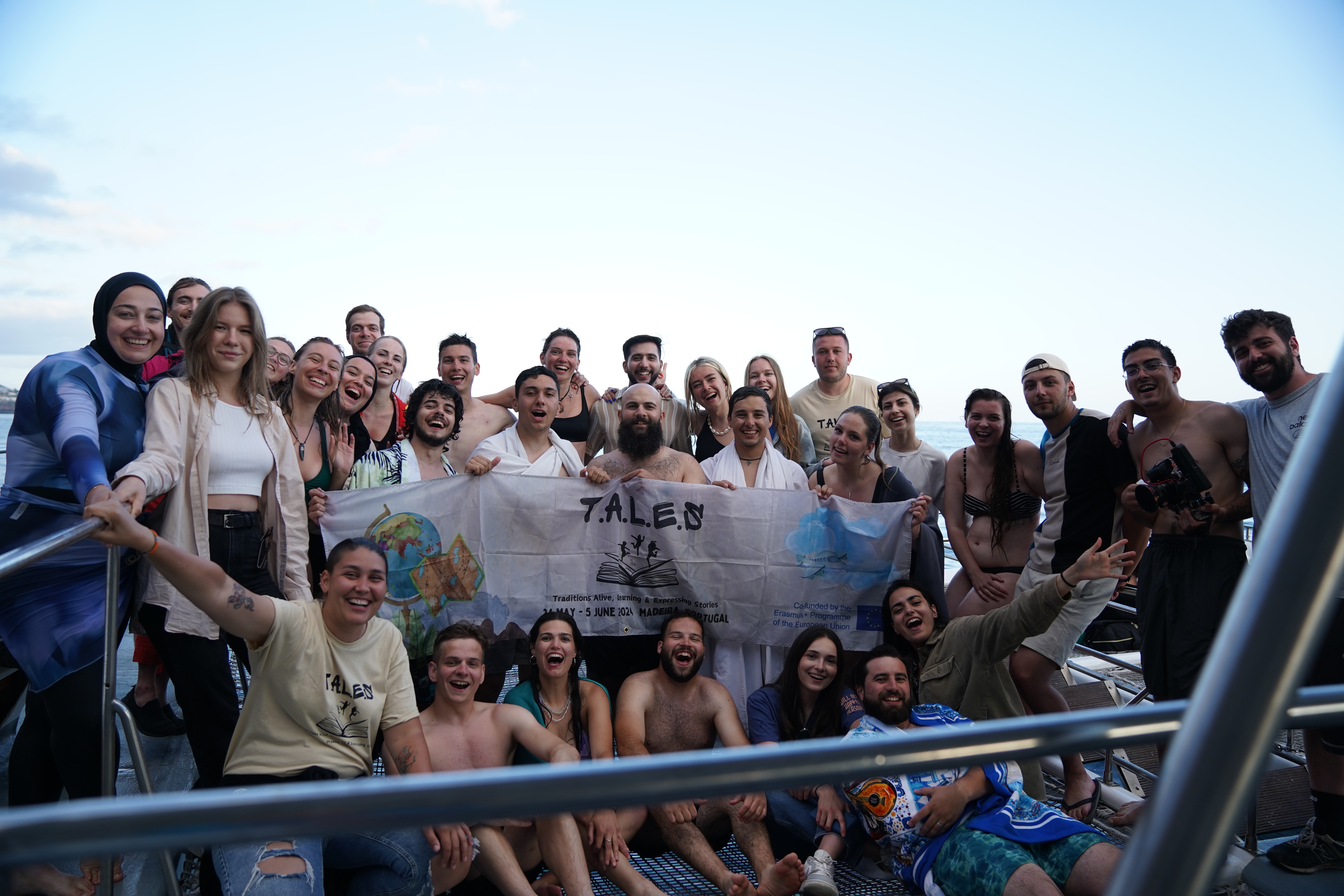 Group of youth participants holding a TALES banner on a boat